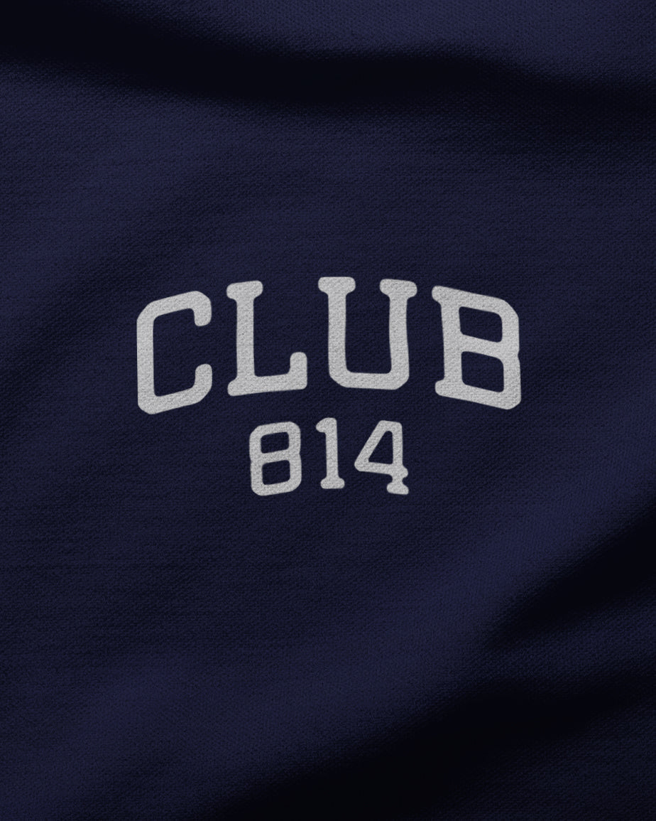 Four women standing together and smiling, wearing matching white t-shirts with purple collegiate-style lettering that reads 'CLUB 814' and blue jeans. The photo has a warm, vintage-filtered look with a beige background.