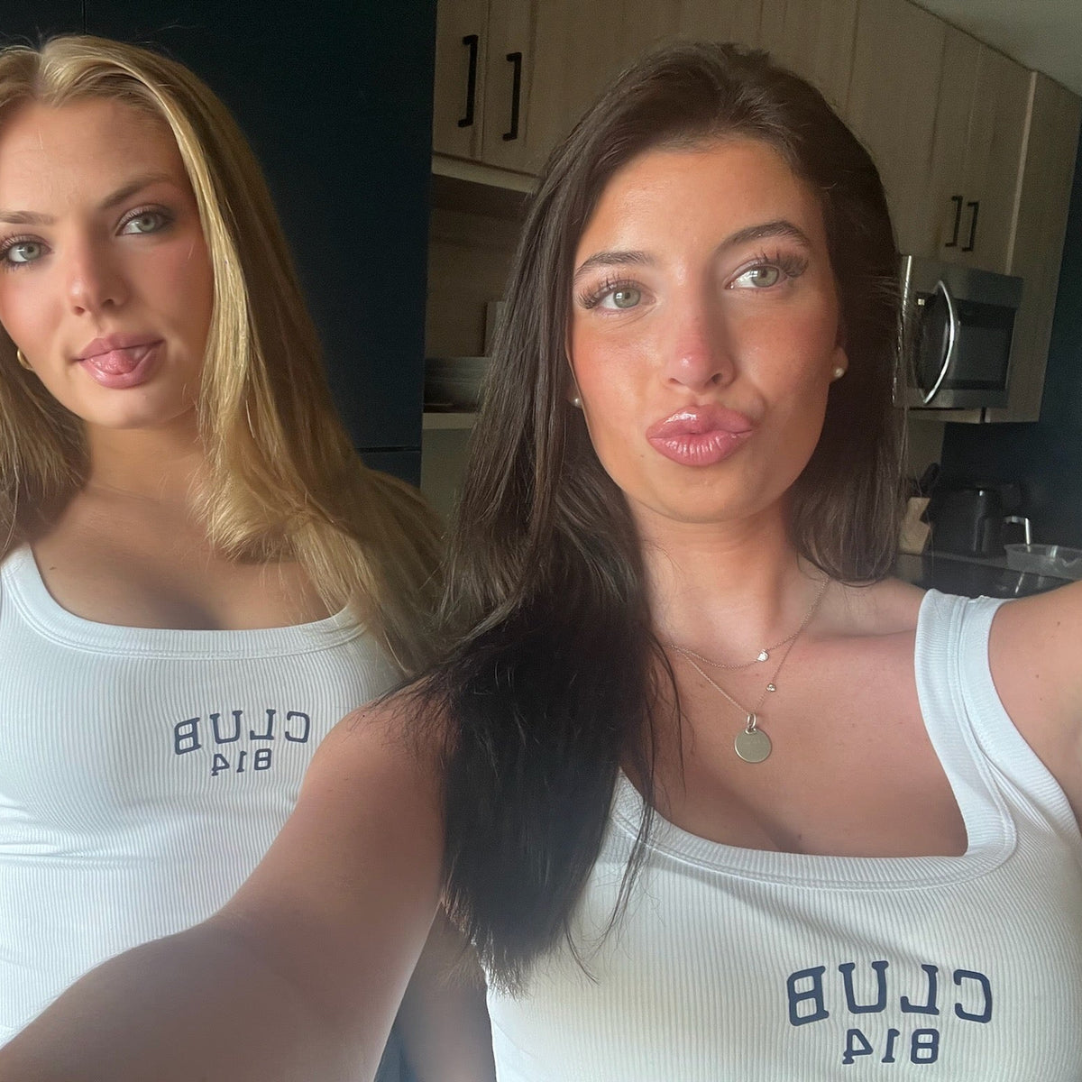 Two women taking a selfie indoors, both wearing white ribbed tank tops with the text 'CLUB 814' printed in navy on the front.